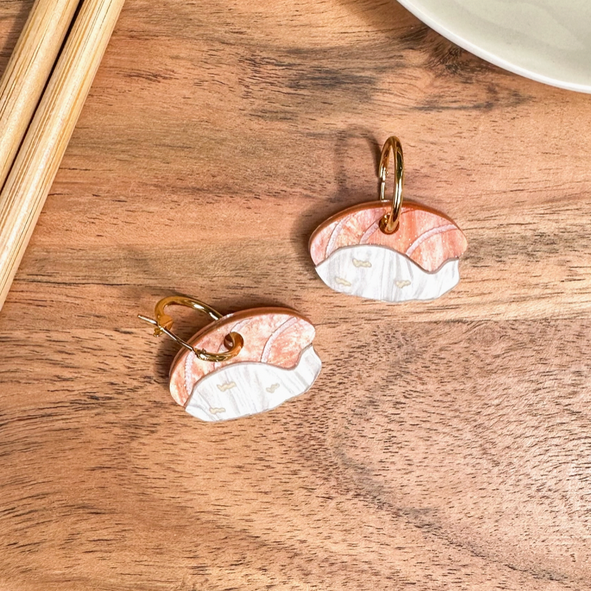Pair of rose gold and silver earrings on a wooden surface